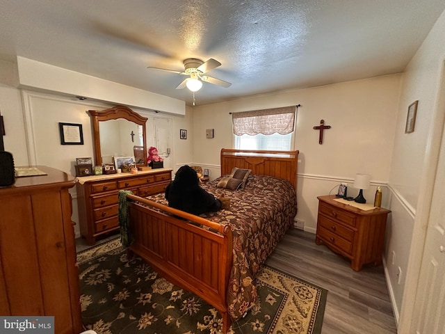 bedroom with hardwood / wood-style flooring, ceiling fan, and a textured ceiling