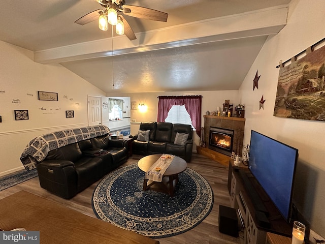 living room with ceiling fan, wood-type flooring, lofted ceiling with beams, and a tile fireplace