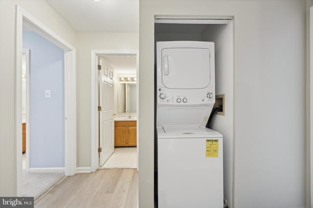 washroom with stacked washer / dryer, sink, and light hardwood / wood-style flooring