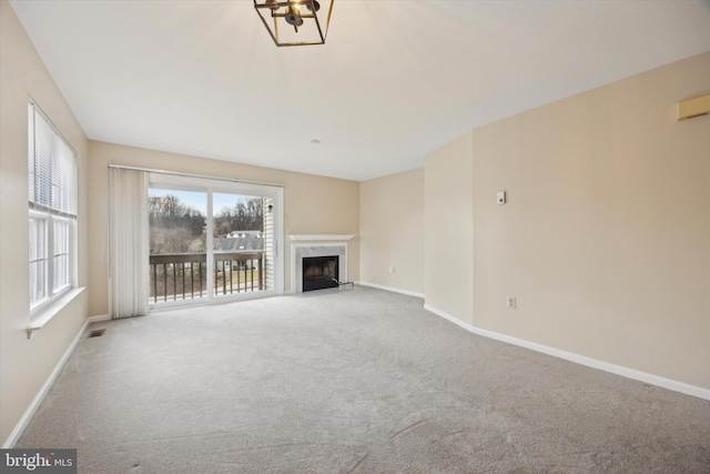 unfurnished living room with a high end fireplace and light colored carpet