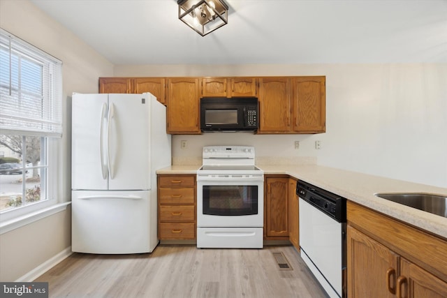 kitchen with light stone countertops, white appliances, and light hardwood / wood-style floors