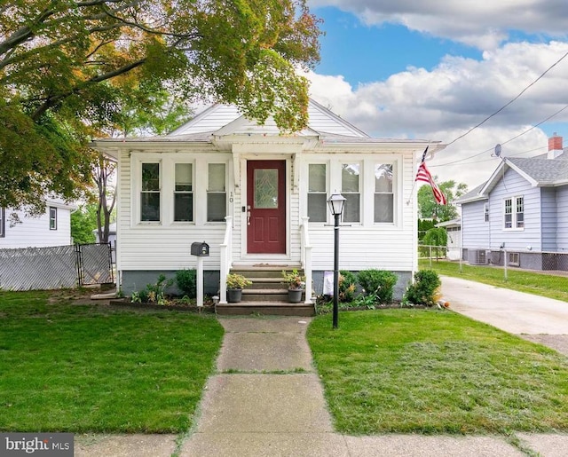 bungalow-style house featuring a front yard and cooling unit