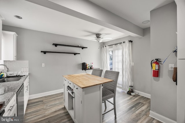 kitchen featuring sink, a breakfast bar area, tasteful backsplash, light stone countertops, and white cabinets