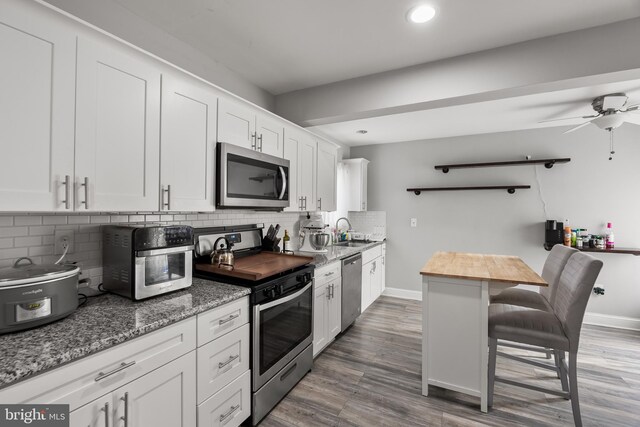 kitchen with stainless steel appliances, white cabinets, and dark stone counters