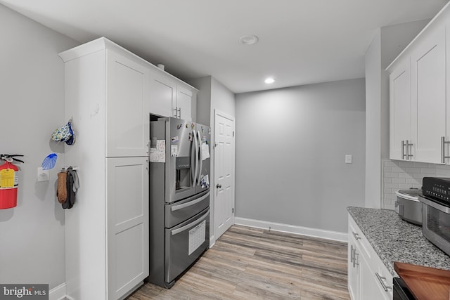 kitchen featuring white cabinetry, stainless steel fridge, light hardwood / wood-style floors, and decorative backsplash