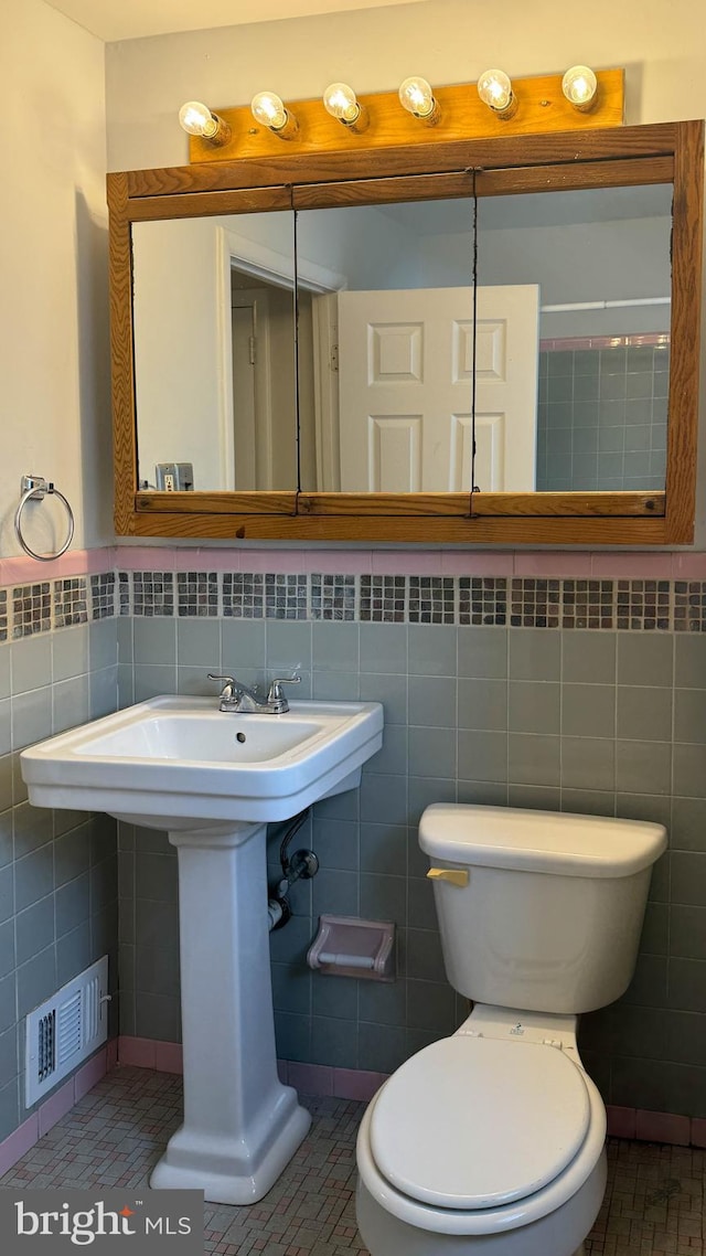 bathroom with tile patterned flooring, tile walls, and toilet