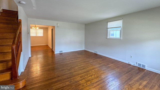 empty room with dark hardwood / wood-style floors and a chandelier