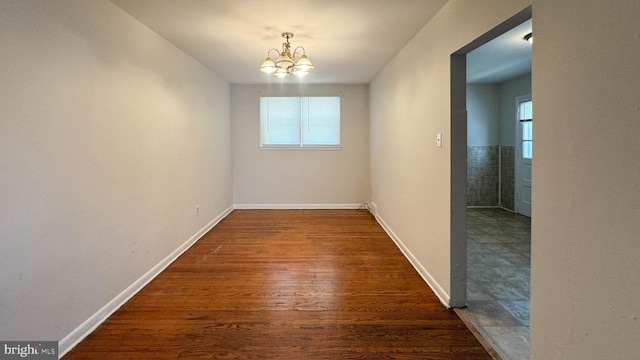 empty room with a chandelier, dark hardwood / wood-style floors, and a healthy amount of sunlight