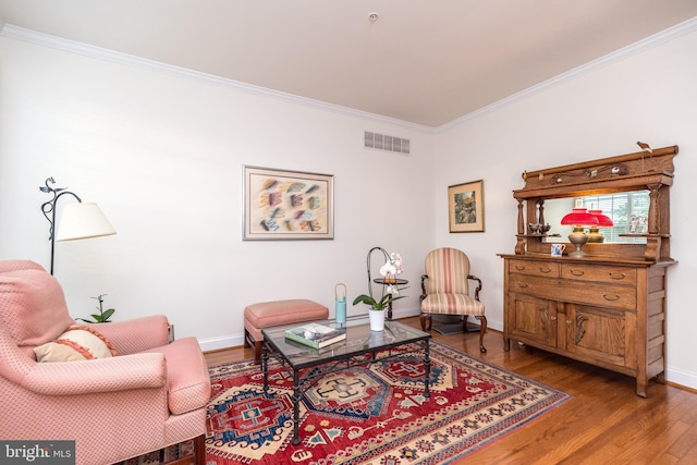 living area featuring crown molding and hardwood / wood-style flooring