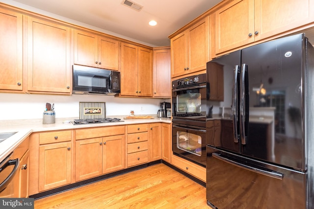 kitchen with light hardwood / wood-style floors and black appliances