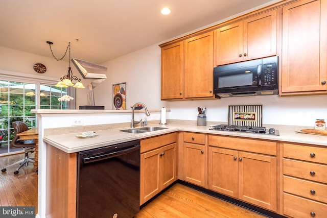 kitchen with sink, light wood-type flooring, kitchen peninsula, pendant lighting, and black appliances