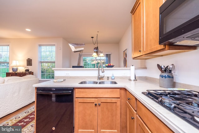 kitchen with plenty of natural light, sink, an inviting chandelier, and black appliances