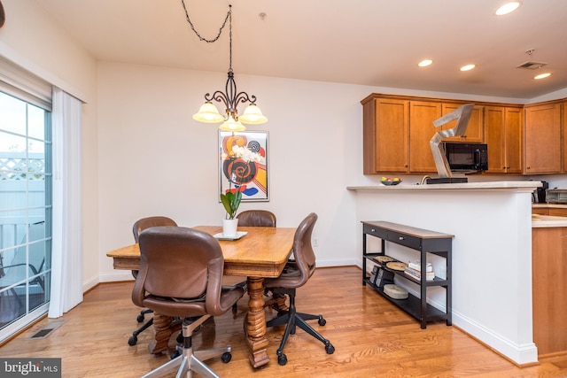 dining area with light hardwood / wood-style floors and a chandelier