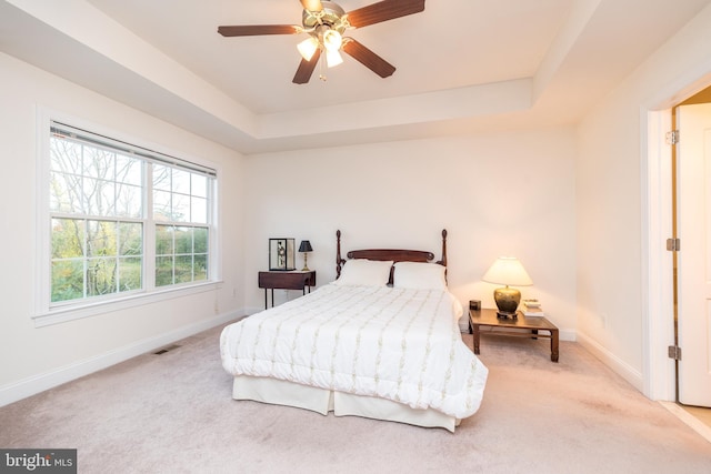 carpeted bedroom featuring ceiling fan and a tray ceiling