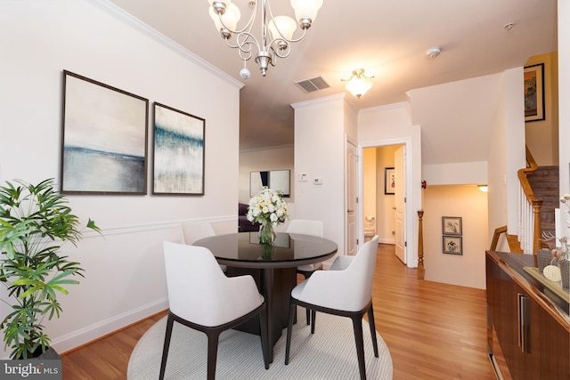 dining area with an inviting chandelier, crown molding, and light hardwood / wood-style flooring