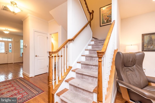 stairs featuring hardwood / wood-style flooring and ornamental molding