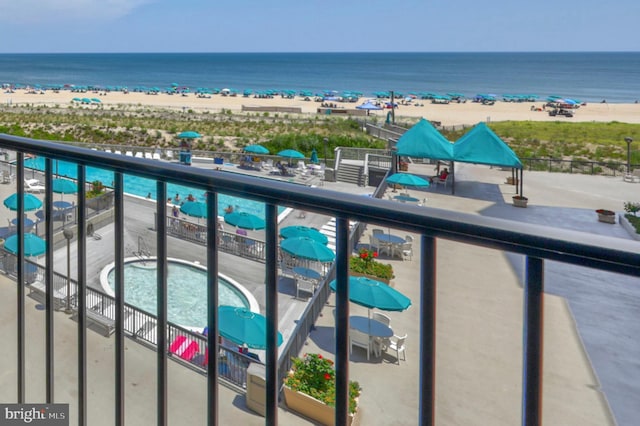 balcony featuring a water view, a beach view, and a jacuzzi