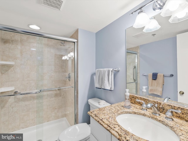 bathroom with vanity, a shower with door, and toilet