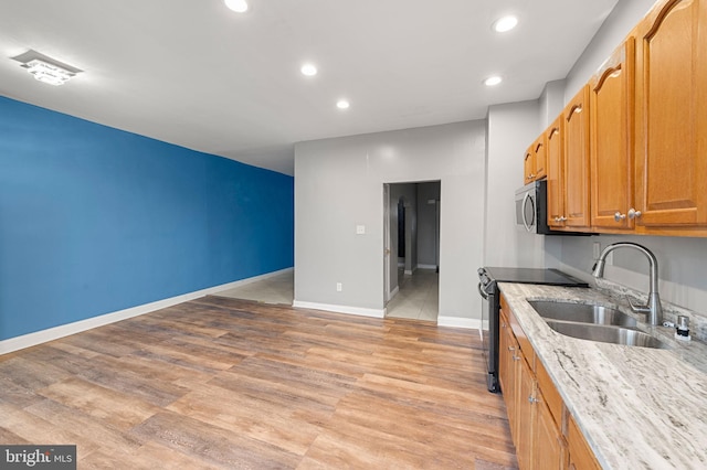 kitchen featuring black / electric stove, light stone countertops, sink, and light wood-type flooring