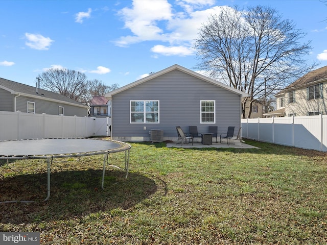 back of house with a trampoline, central AC unit, a yard, and a patio