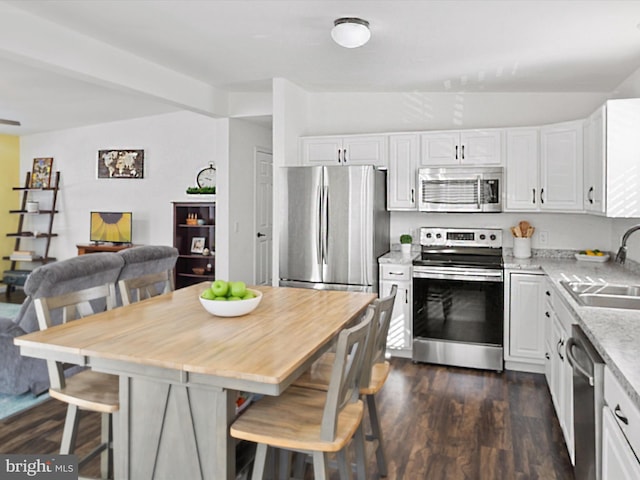 kitchen with sink, appliances with stainless steel finishes, white cabinetry, a center island, and a kitchen bar