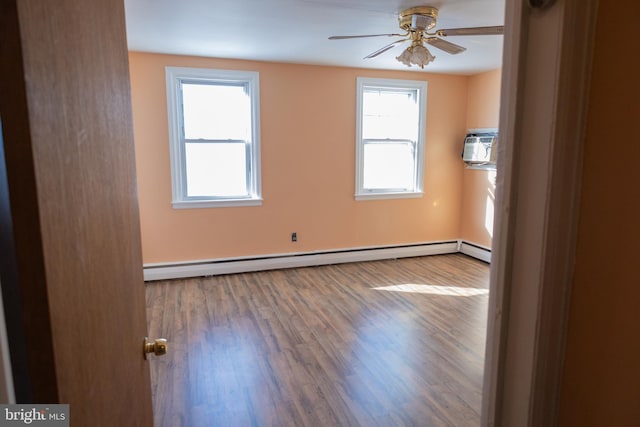 spare room featuring hardwood / wood-style floors, a baseboard radiator, a wall unit AC, and ceiling fan