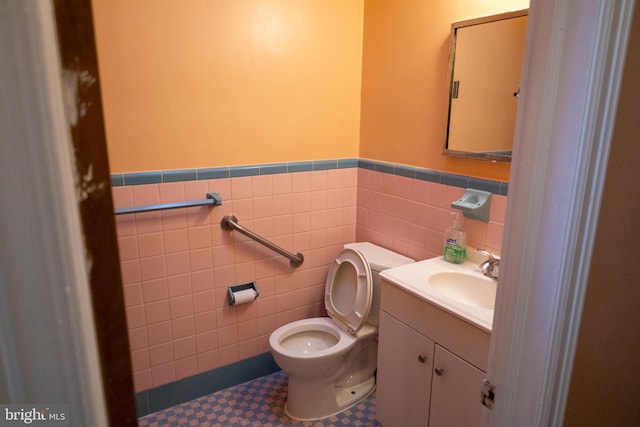 bathroom with vanity, toilet, and tile walls