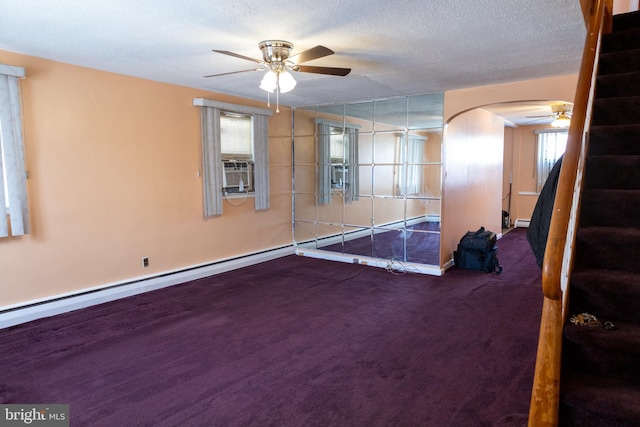 carpeted empty room with ceiling fan, a baseboard radiator, a textured ceiling, and a wealth of natural light