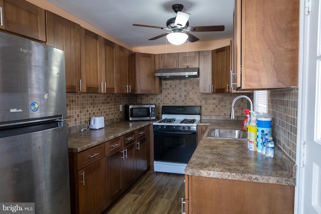 kitchen with sink, appliances with stainless steel finishes, backsplash, dark hardwood / wood-style floors, and extractor fan