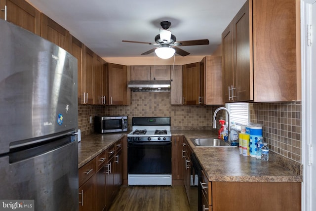 kitchen with appliances with stainless steel finishes, sink, dark wood-type flooring, and backsplash