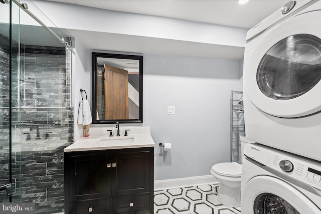 bathroom featuring an enclosed shower, stacked washing maching and dryer, vanity, and toilet