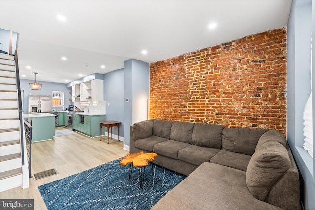 living room with brick wall and light hardwood / wood-style floors