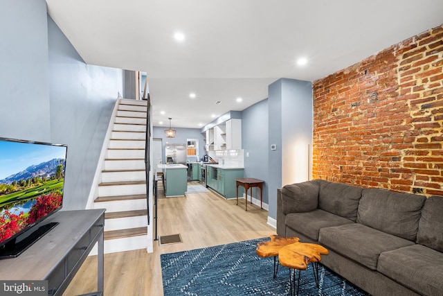 living room with light hardwood / wood-style floors and brick wall