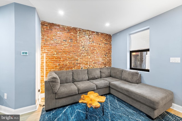 living room featuring hardwood / wood-style flooring and brick wall