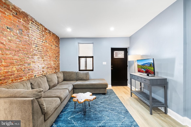 living room with brick wall and light wood-type flooring