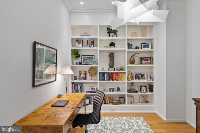 office space with built in shelves, ornamental molding, and light hardwood / wood-style flooring