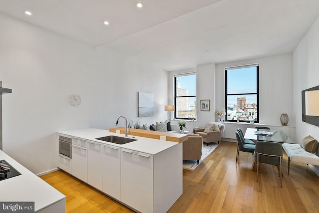 kitchen featuring sink, light hardwood / wood-style floors, kitchen peninsula, and white cabinets