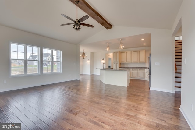 unfurnished living room featuring sink, vaulted ceiling with beams, ceiling fan with notable chandelier, and light wood-type flooring