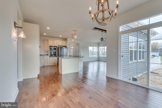 kitchen featuring sink, light hardwood / wood-style floors, a kitchen island with sink, stainless steel appliances, and ceiling fan with notable chandelier