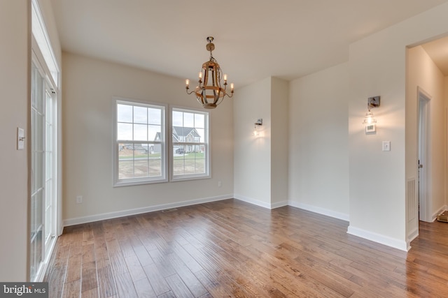 empty room with an inviting chandelier and hardwood / wood-style floors