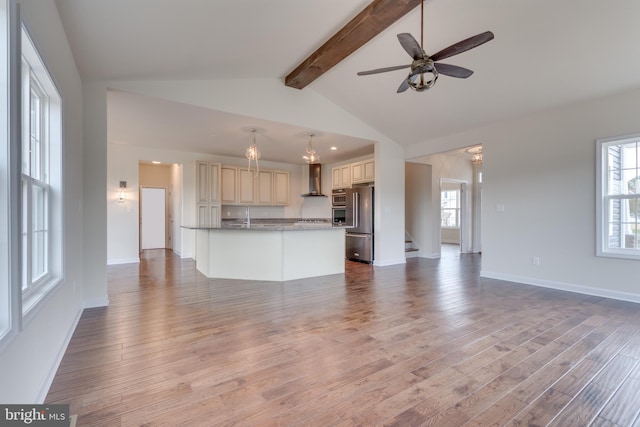 unfurnished living room featuring lofted ceiling with beams, plenty of natural light, and light hardwood / wood-style flooring