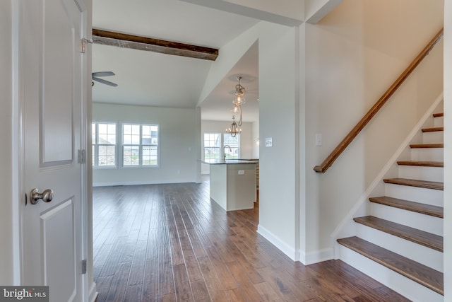 stairway with an inviting chandelier, sink, beam ceiling, and hardwood / wood-style floors