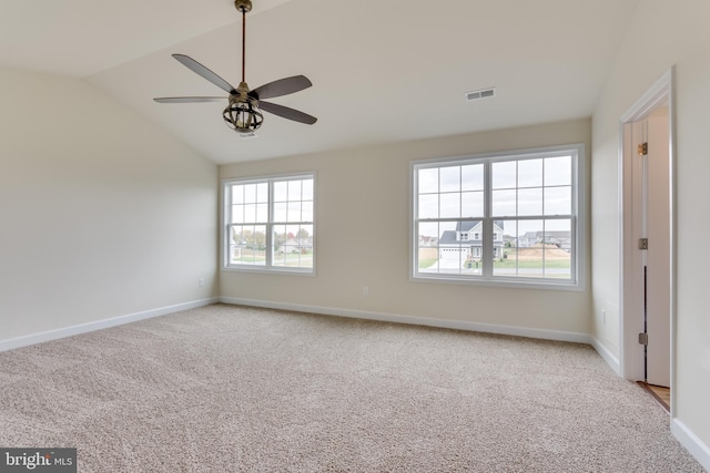 carpeted empty room featuring vaulted ceiling, a healthy amount of sunlight, and ceiling fan