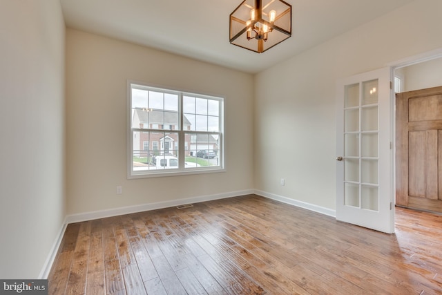 empty room featuring a chandelier and light wood-type flooring