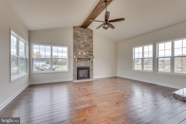 unfurnished living room featuring vaulted ceiling with beams, a stone fireplace, wood-type flooring, and ceiling fan