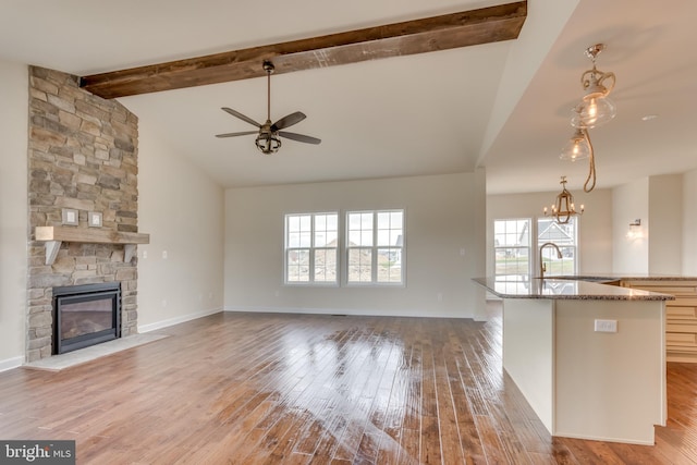 kitchen with sink, beam ceiling, hanging light fixtures, and light wood-type flooring