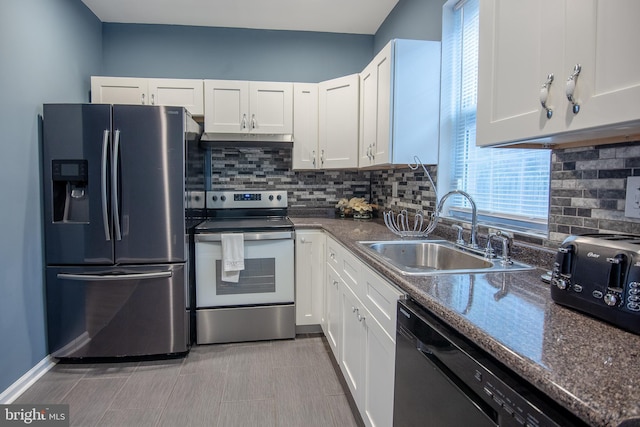 kitchen with sink, appliances with stainless steel finishes, dark stone countertops, white cabinets, and decorative backsplash