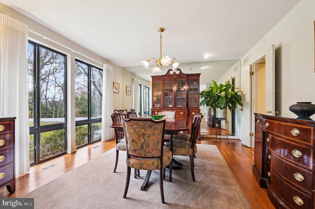 dining space with a chandelier, wood finished floors, and visible vents