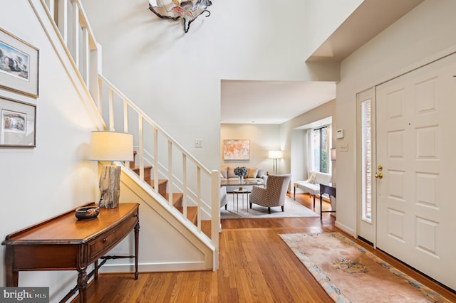 entrance foyer with stairs, wood finished floors, and a towering ceiling