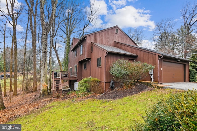 view of side of home with stairway, roof with shingles, an attached garage, gravel driveway, and a deck